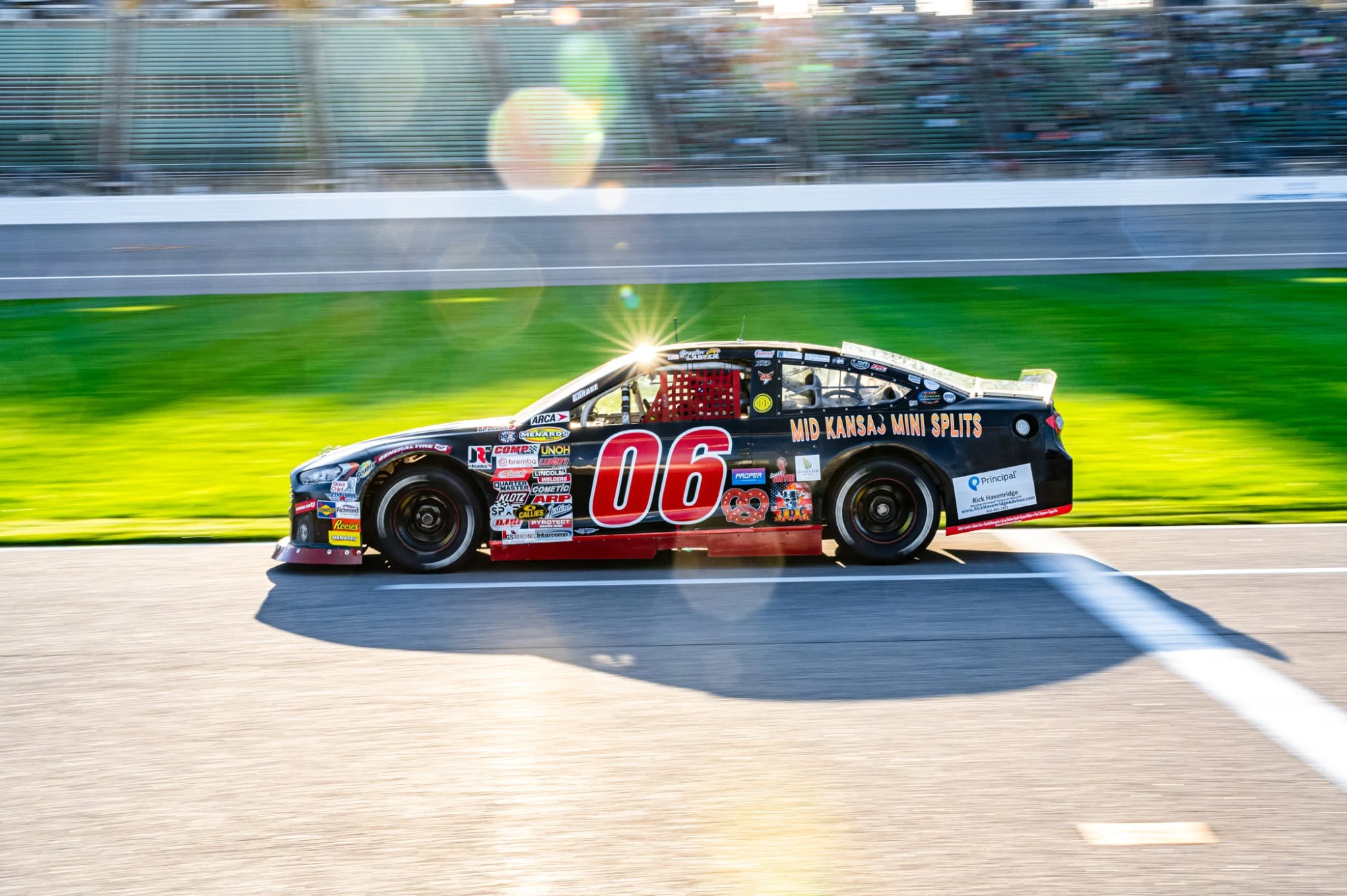 Black and red No. 06 Mid Kansas Mini Splits Ford at speed with the sun flaring over the roof